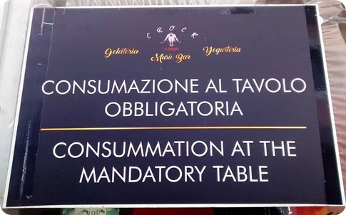 cartello con le scritte CONSUMAZIONE AL TAVOLO OBBLIGATORIA - CONSUMMATION AT THE MANDATORY TABLE