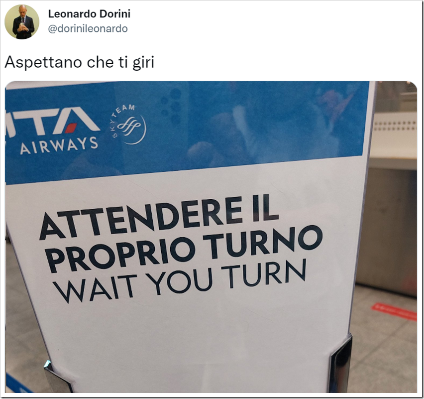 Cartello di ITA Airways, presumibilmente al check-in o al gate, con scritta ATTENDERE IL PROPRIO TURNO e traduzione maldestra in inglese WAIT YOU TURN